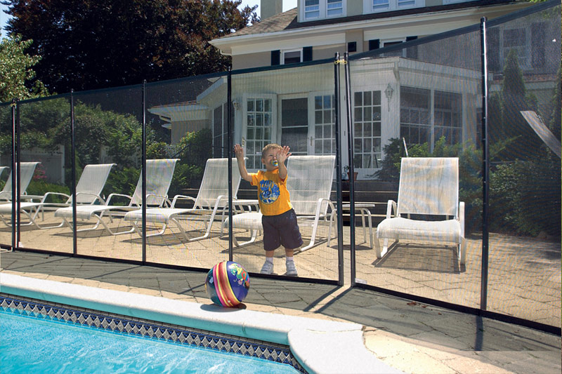 baby standing outside of a pool next to BABY-LOC pool fencing