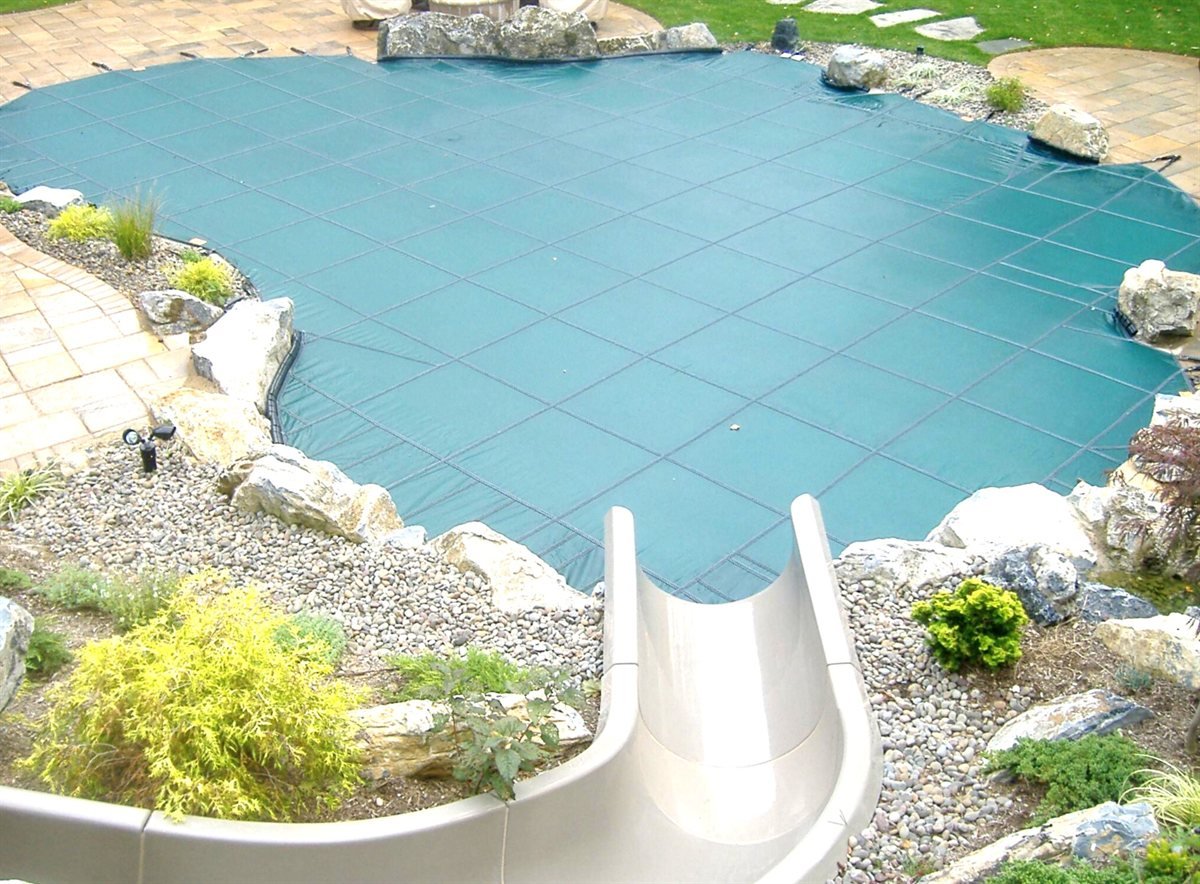 Green LOOP-LOC safety pool cover installed over a backyard pool